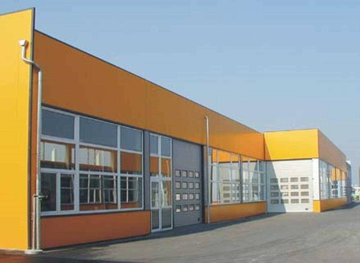 Ansicht eines modernen Industriegebäudes mit orangefarbenen Akzenten und mehreren Rolltoren.