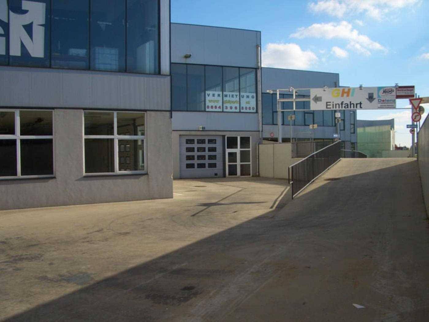 Zufahrtsrampe zu einem Gewerbegebäude mit Rolltor und angrenzenden Parkmöglichkeiten auf dem Gelände.