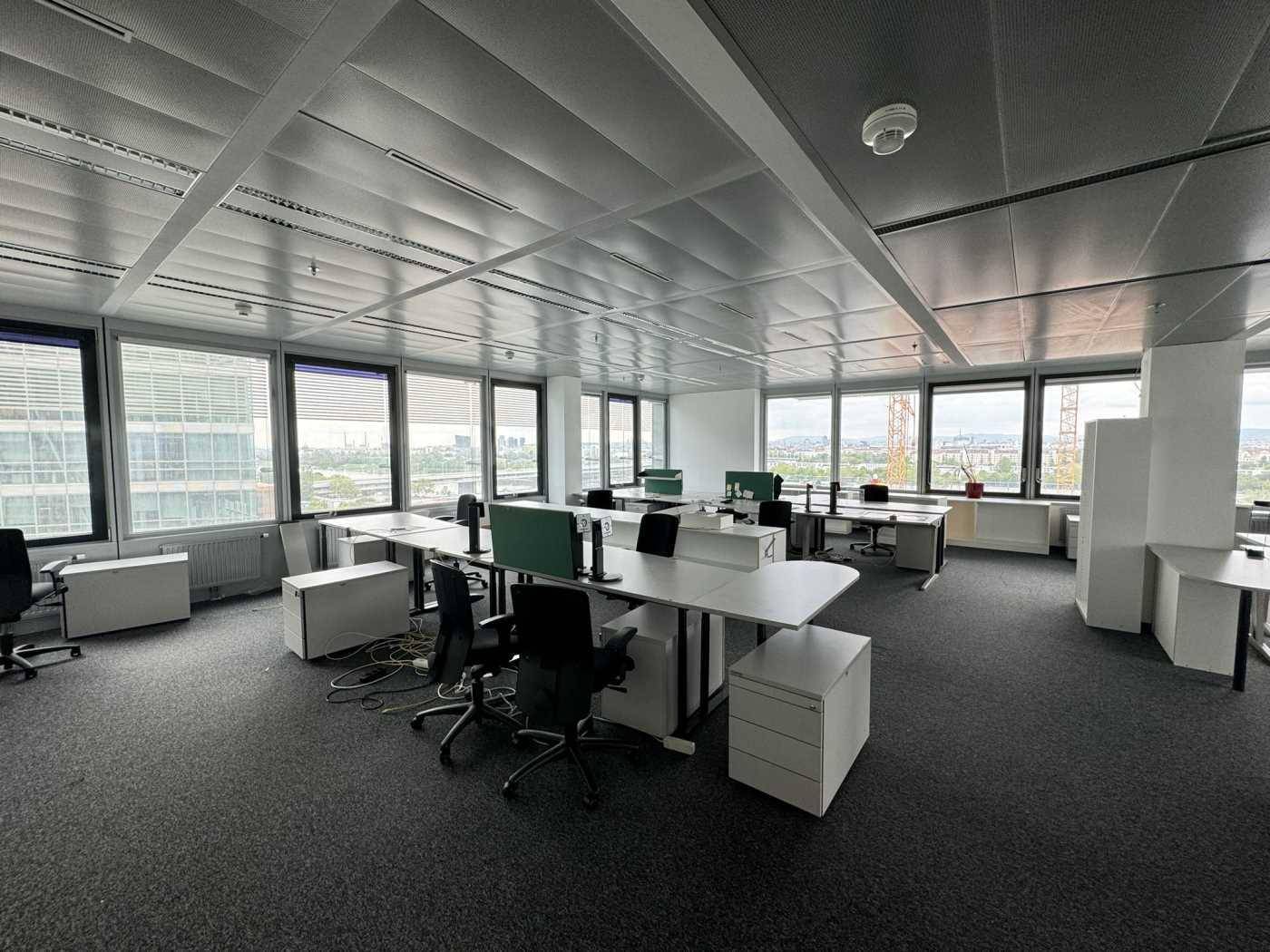 Geräumiges Büro mit mehreren Arbeitsplätzen, Teppichboden und weitem Ausblick auf die Umgebung.