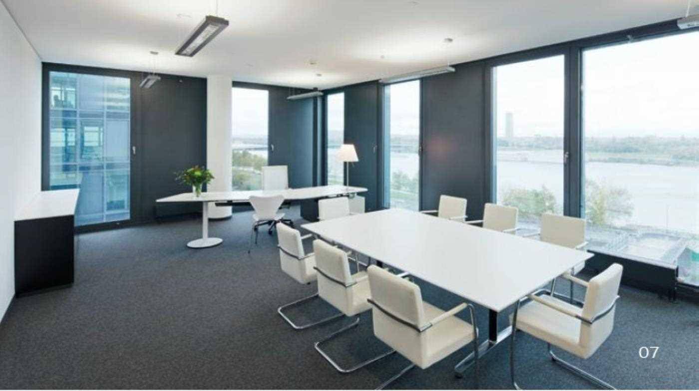 Helles Büro mit großen Fenstern und Blick auf das Wasser, ausgestattet mit modernen Tischen und Stühlen.