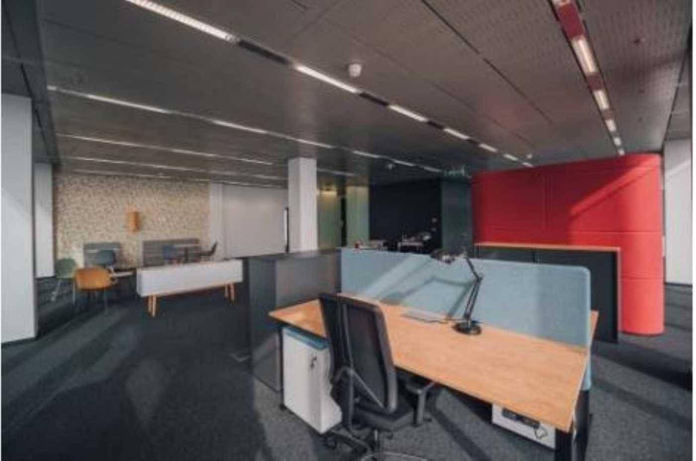 Offenes Büro mit modularen Arbeitsplätzen, Teppichboden und farbigen Akzentwänden.