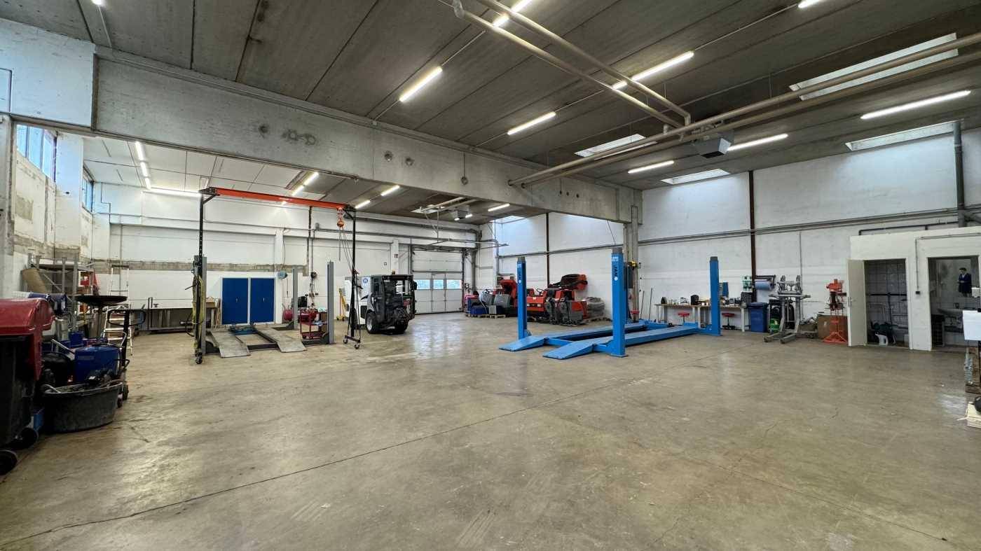 Geräumige Werkstatt mit mehreren Hebebühnen, hohen Decken und industrieller Beleuchtung.