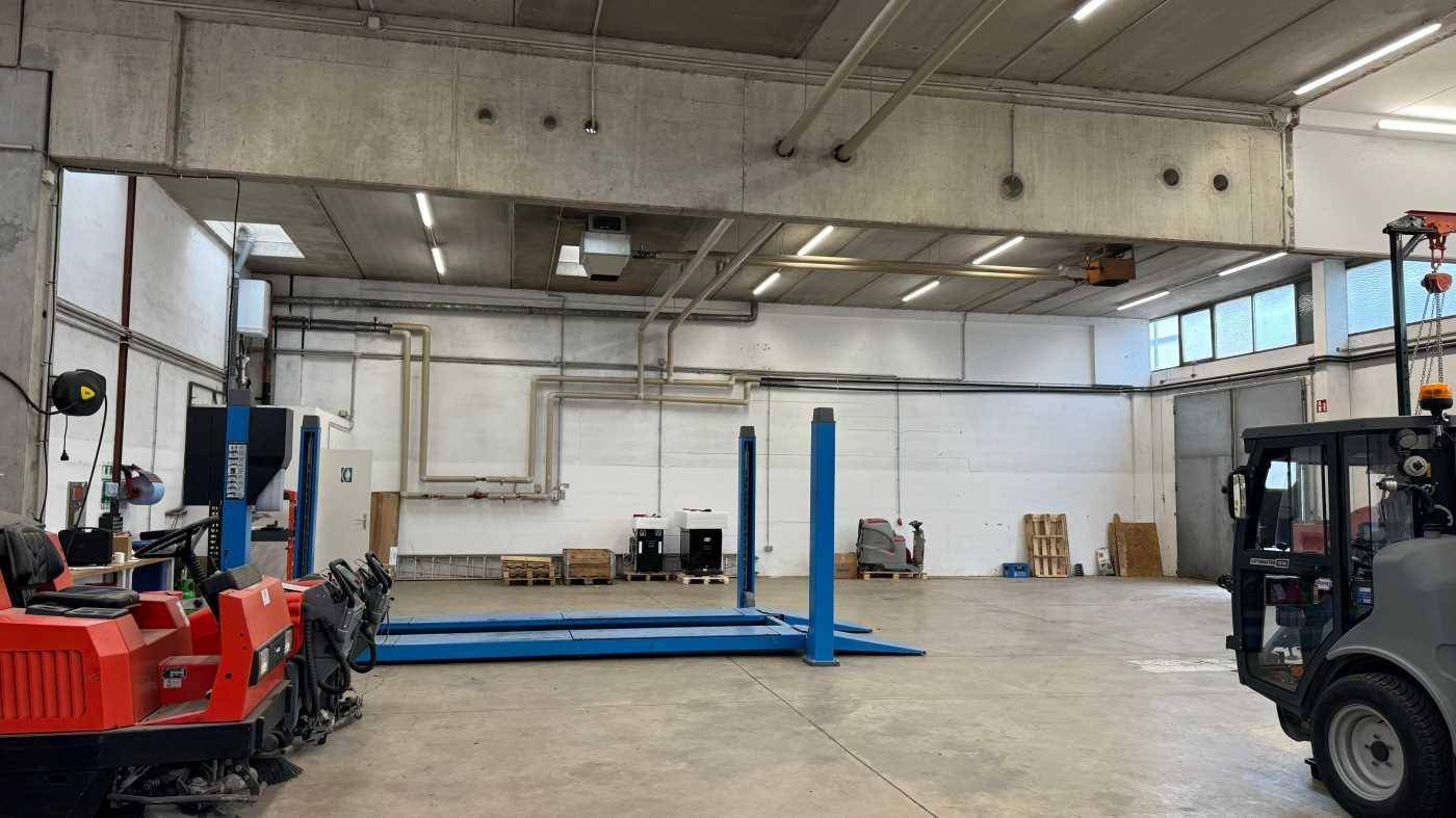 Werkstattbereich mit Hebebühnen, hohen Decken und großen Fenstern für Tageslicht.