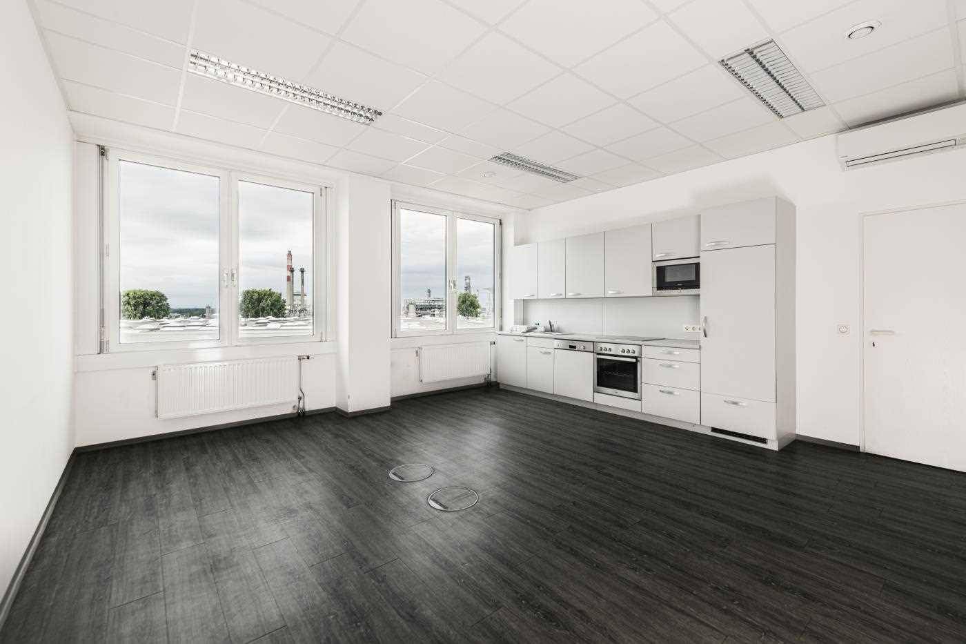 Moderne Einbauküche mit weißen Schränken, dunklem Vinylboden und großen Fenstern mit Ausblick.