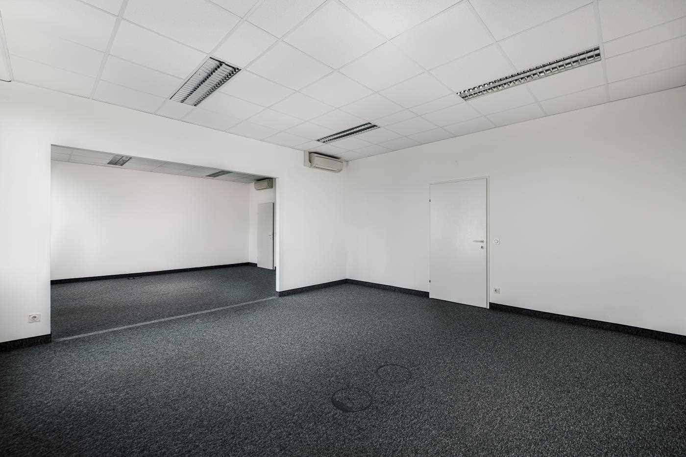 Leerer Büroraum mit Teppichboden, abgehängter Decke und Klimaanlage, bereit zur individuellen Gestaltung.