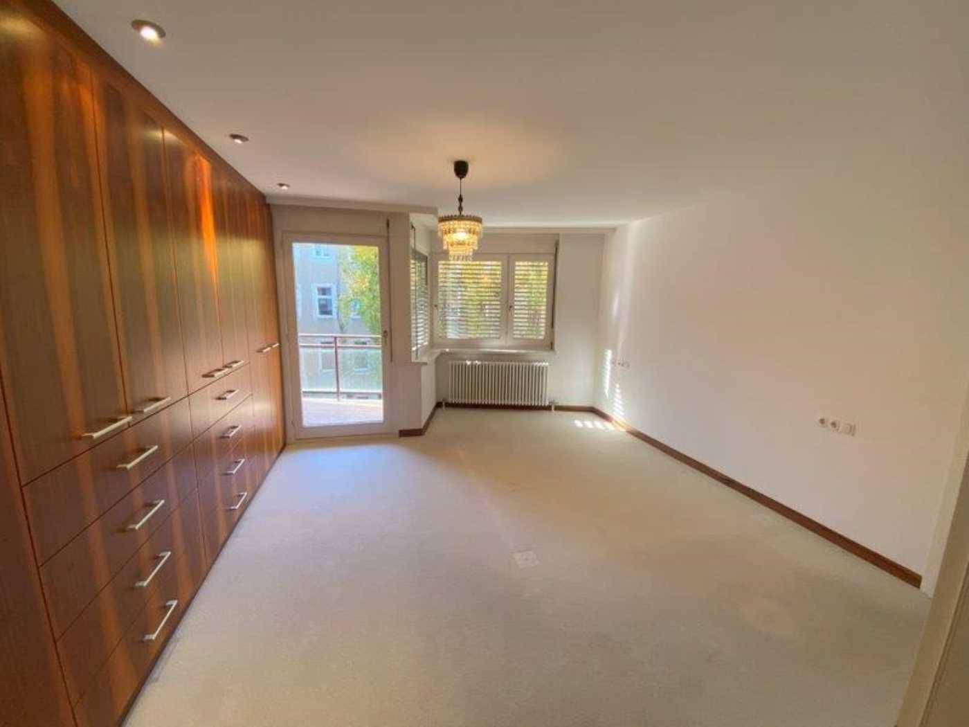 Geräumiges Schlafzimmer mit umfangreichen Einbauschränken, Teppichboden und Zugang zum Balkon.