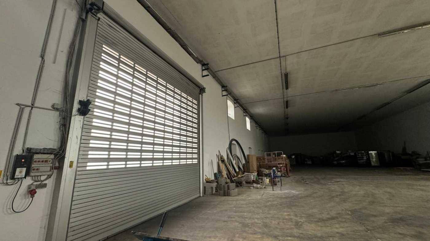 Innenansicht eines großen Rolltors in einer Lagerhalle mit Betonboden und hohen Decken.