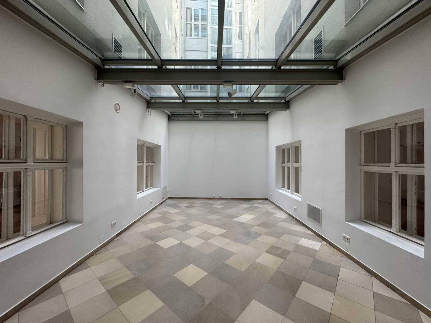Innenhof mit Glasdach und gemustertem Fliesenboden, der viel natürliches Licht in den Raum bringt.