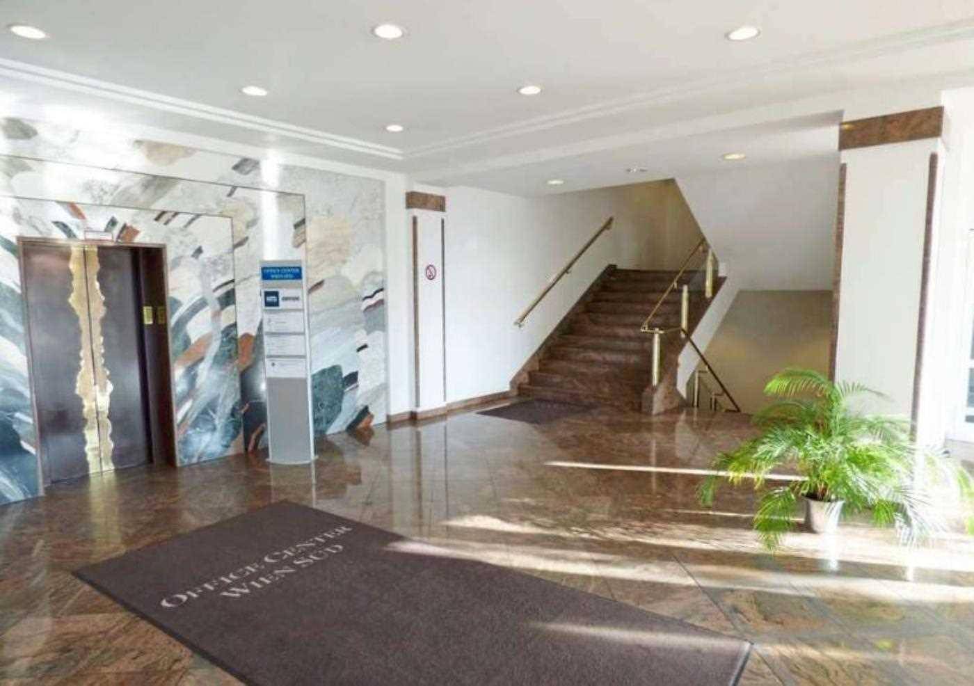Geräumige Lobby mit Marmorboden, Aufzug und eleganter Treppe, die zu den oberen Etagen führt.
