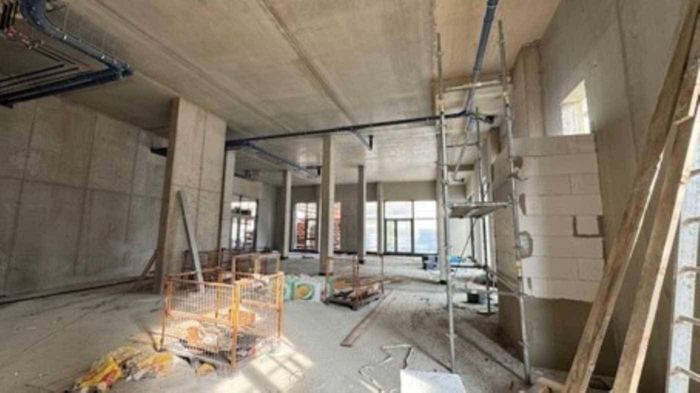 Weiterer Blick in den Rohbau mit Betonwänden, Gerüst und Baumaterialien, der den Fortschritt der Bauarbeiten zeigt.