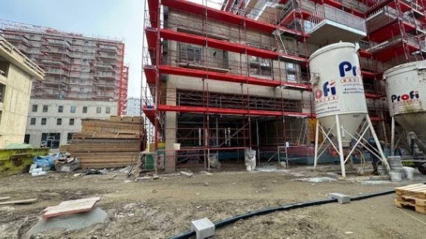 Außenansicht eines im Bau befindlichen Gebäudes mit rotem Gerüst und Baustellenausrüstung.