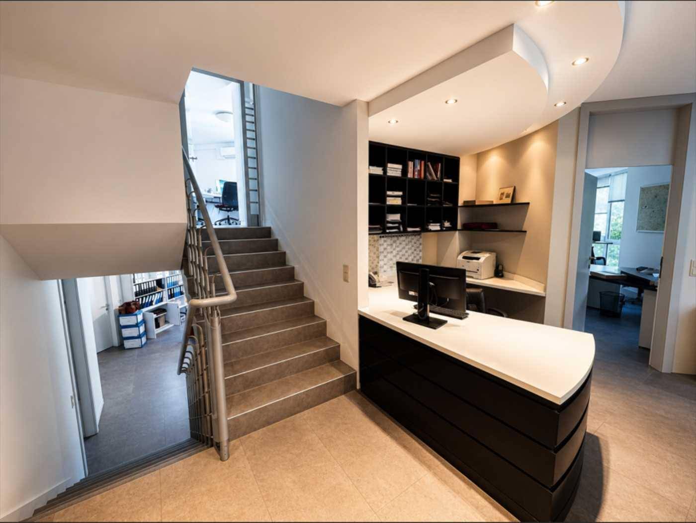 Empfangsbereich mit geschwungener Theke, Treppe zu einer oberen Etage und Regalen.