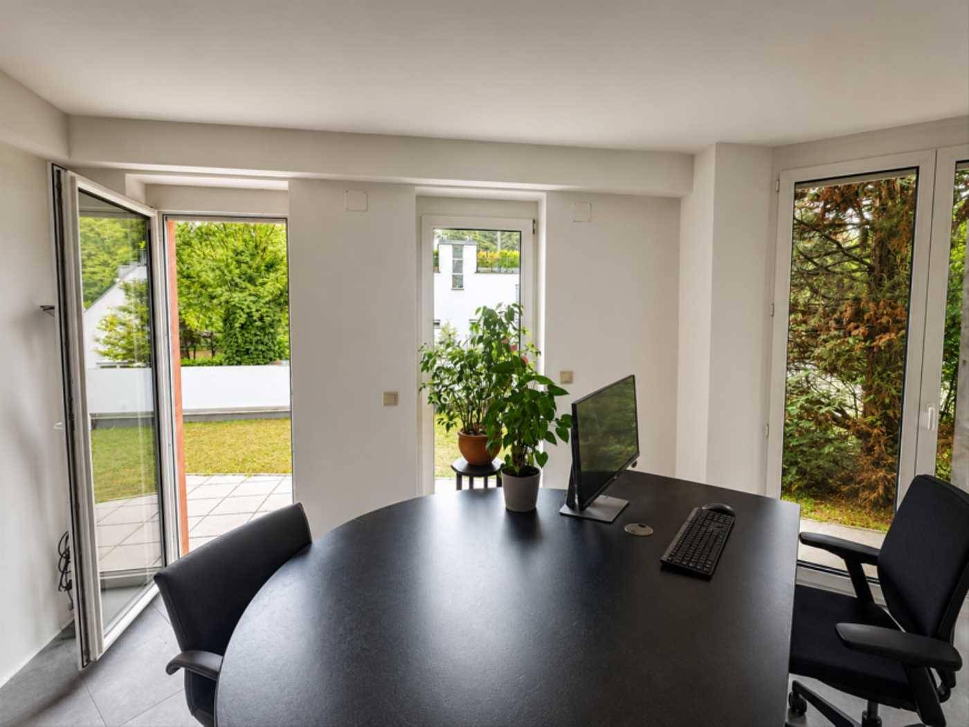 Büro mit Zugang zu einer Terrasse oder einem Garten, umgeben von viel Grün und Tageslicht.