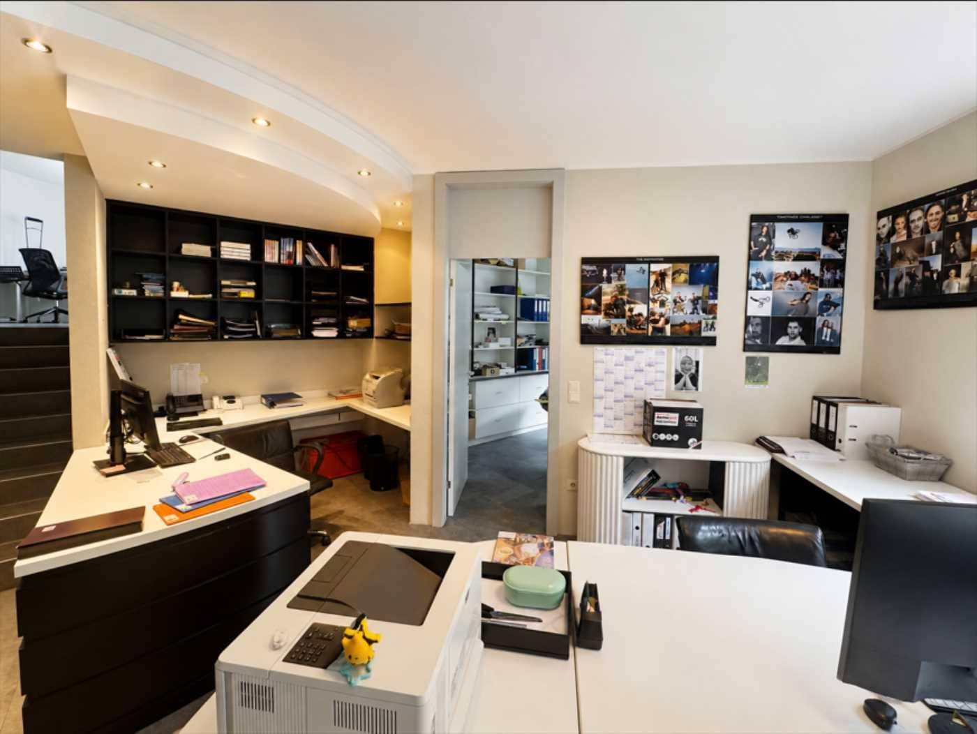 Geräumiges Büro mit mehreren Arbeitsplätzen, Regalen und viel Stauraum für Akten.