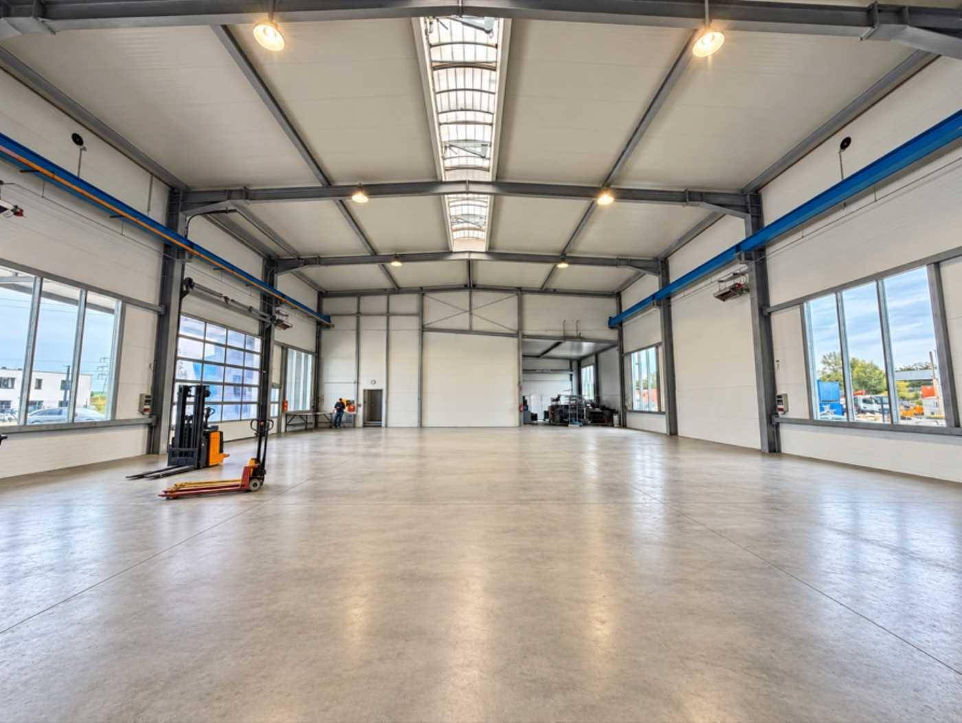 Weitläufige Industriehalle mit viel Tageslicht, robustem Betonboden und sichtbaren Stahlträgern, bereit zur Nutzung.