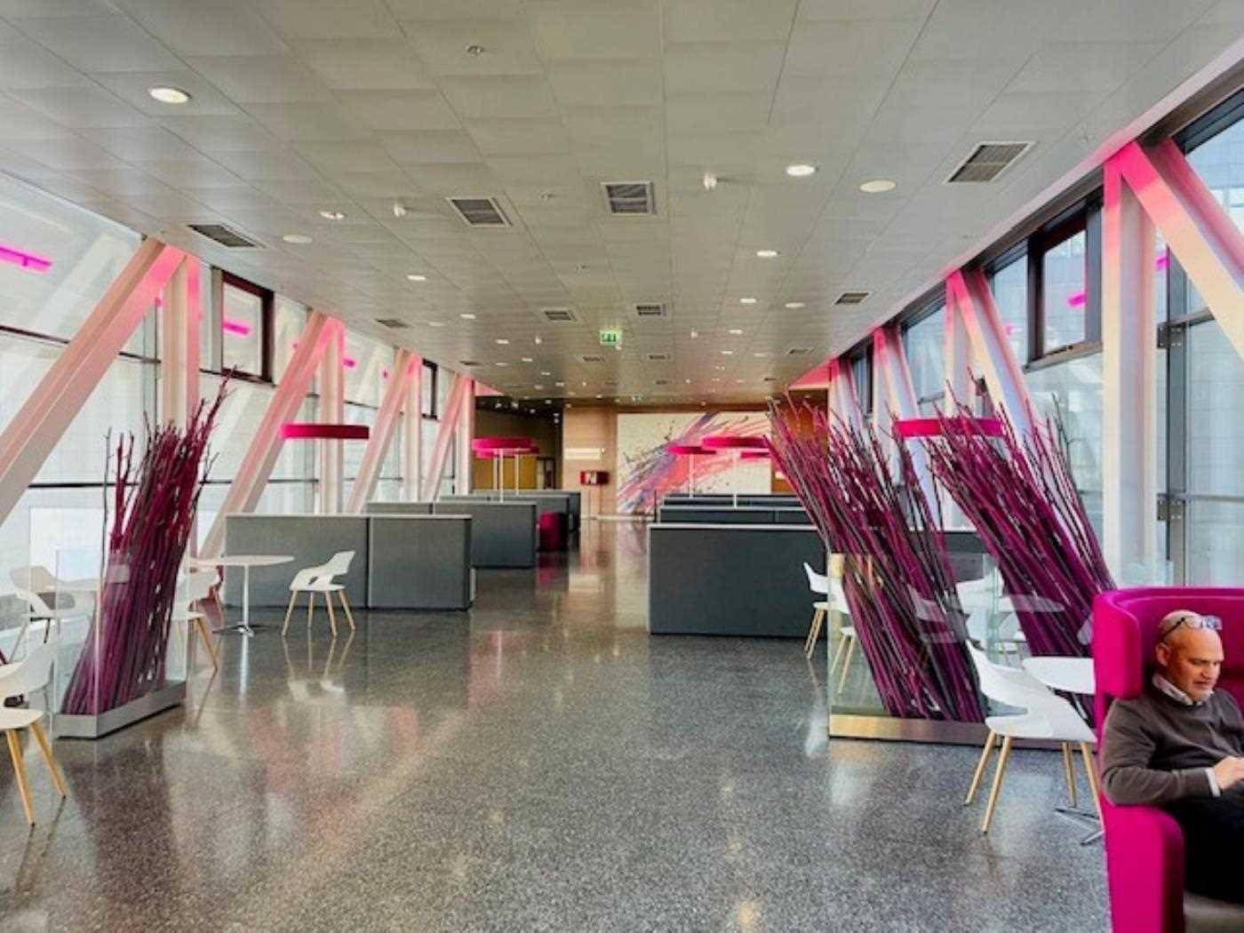 Moderner Loungebereich mit pinken Akzenten, poliertem Betonboden und großen Fenstern.
