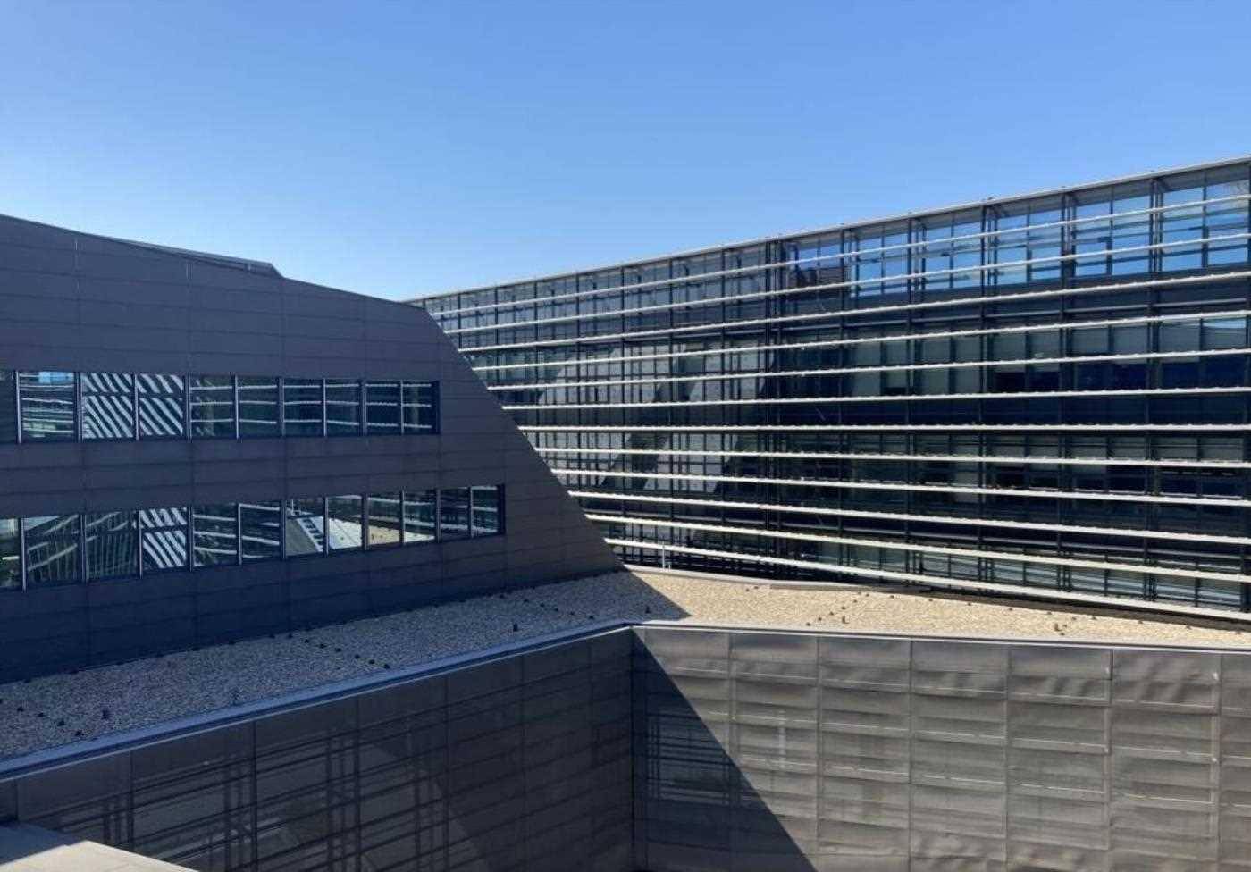 Fassade des modernen Bürogebäudes mit dunklen Paneelen und reflektierenden Glasfenstern.