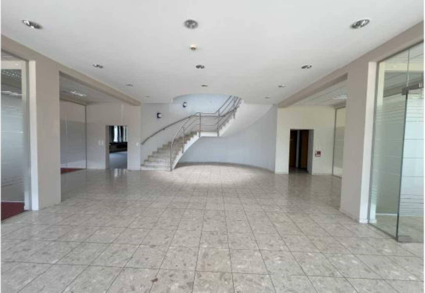 Geräumige Eingangshalle mit Fliesenboden und einer elegant geschwungenen Treppe.
