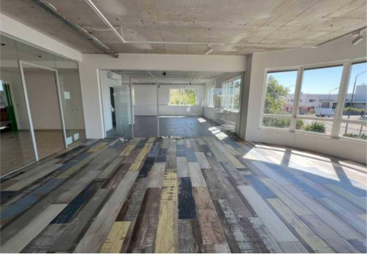 Sonniger Bürobereich mit einzigartigem Dielenboden, Glasabtrennungen und moderner Decke.