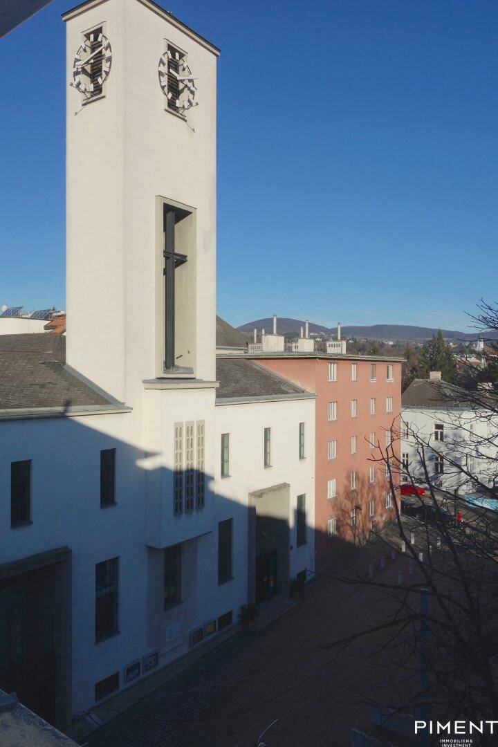 Ansicht eines Gebäudes mit Turm und umliegender Architektur unter blauem Himmel.
