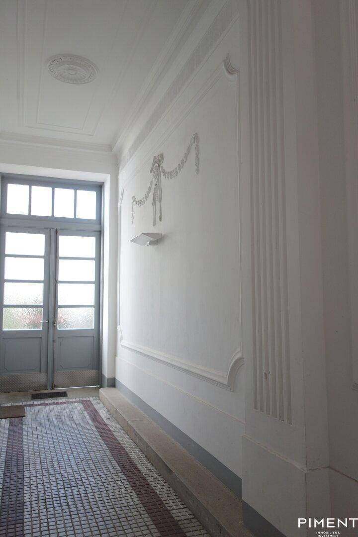 Eleganter Eingangsbereich mit Stuckdecke, verzierten Wänden und gemustertem Fliesenboden.