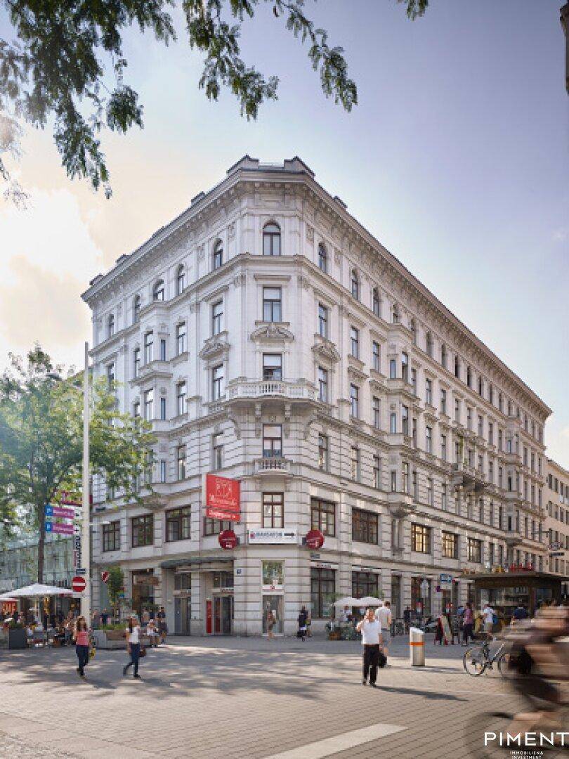 Historisches Eckgebäude mit klassischer Architektur, großen Fenstern und belebter Straße.