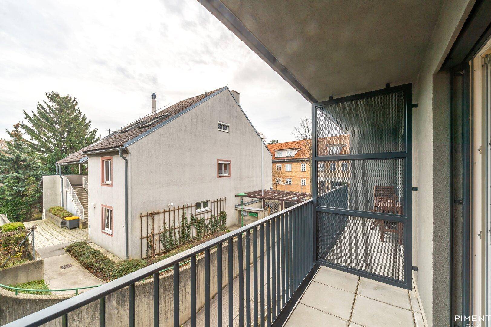 Balkon mit Fliesenboden und Blick auf die umliegenden Gebäude und Grünflächen.