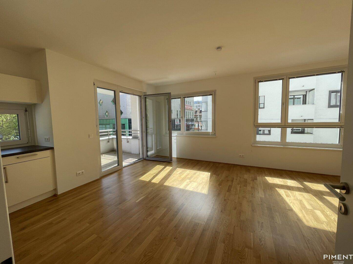 Heller Wohn- und Essbereich mit Parkettboden und Zugang zum Balkon, ideal für geselliges Beisammensein.