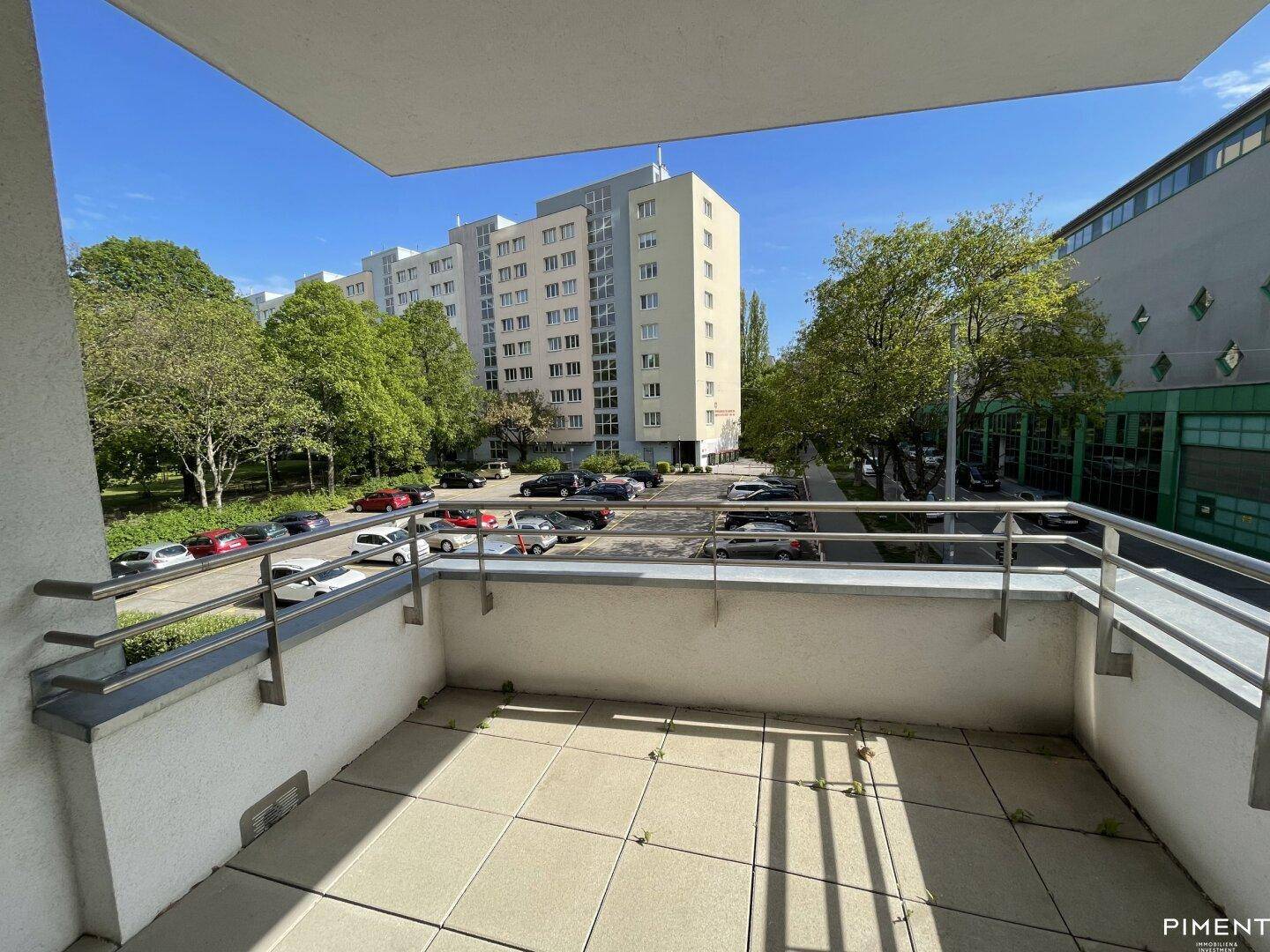 Geräumiger Balkon mit Fliesenboden und Blick auf die umliegenden Gebäude und Parkplätze.