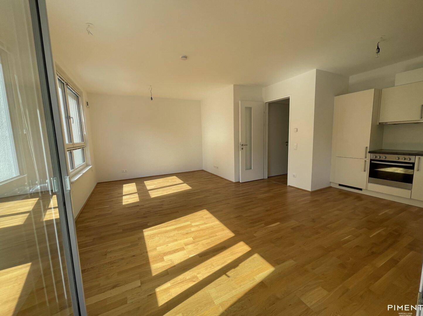 Lichtdurchfluteter Wohnbereich mit Holzboden und viel Tageslicht durch große Fenster.