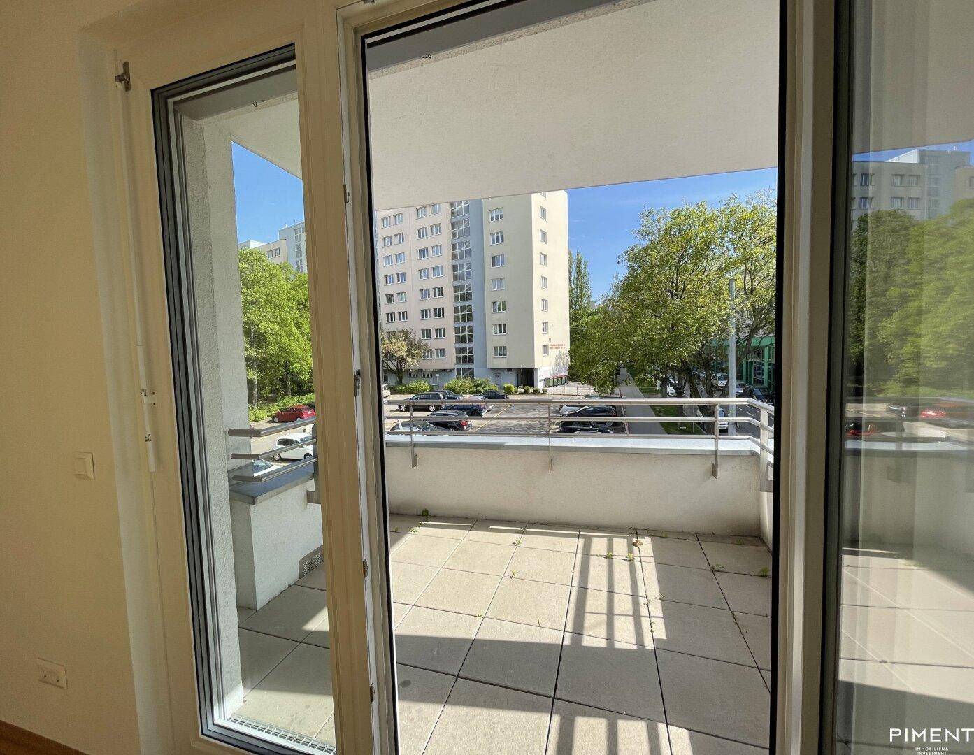 Zugang zum Balkon vom Wohnbereich aus, mit Blick auf die umliegende Bebauung.