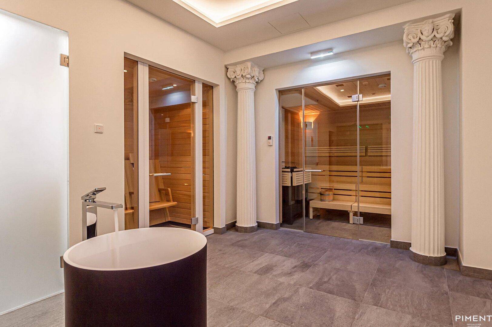 Luxuriöser Wellnessbereich mit zwei Saunen, einer freistehenden Badewanne und klassischen Säulen.
