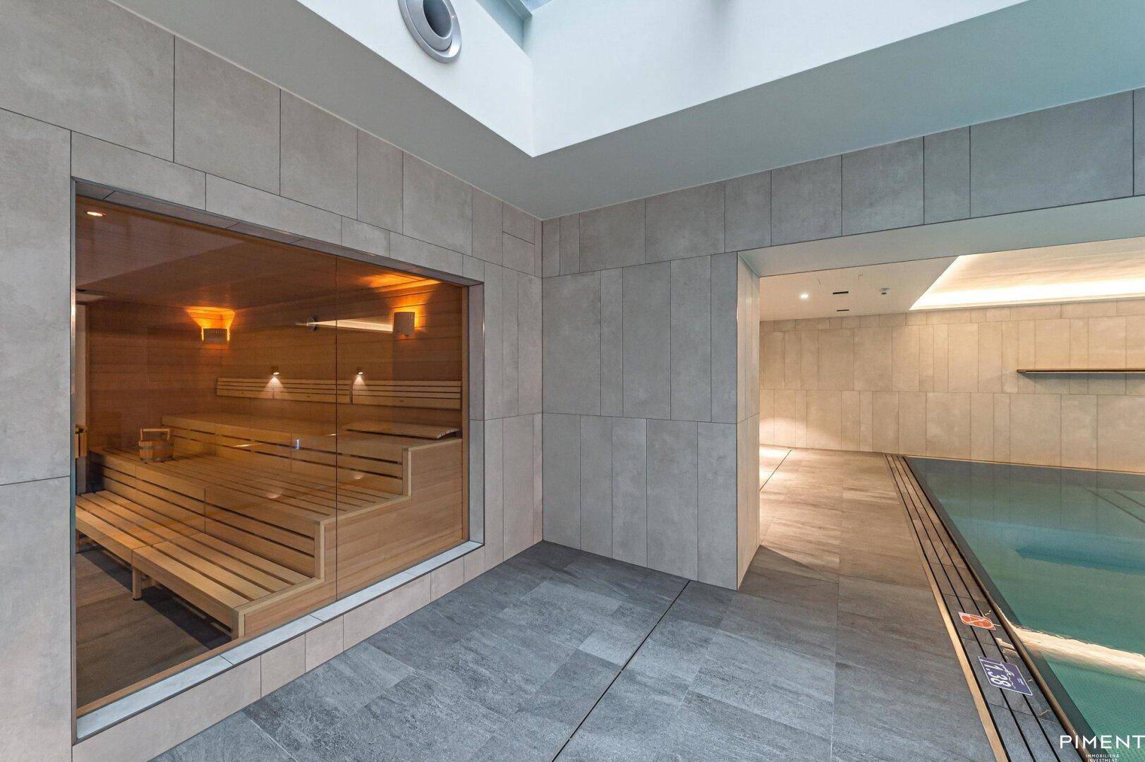 Moderne Sauna mit Holzbänken und Glasfront, direkt neben dem Innenpool gelegen.