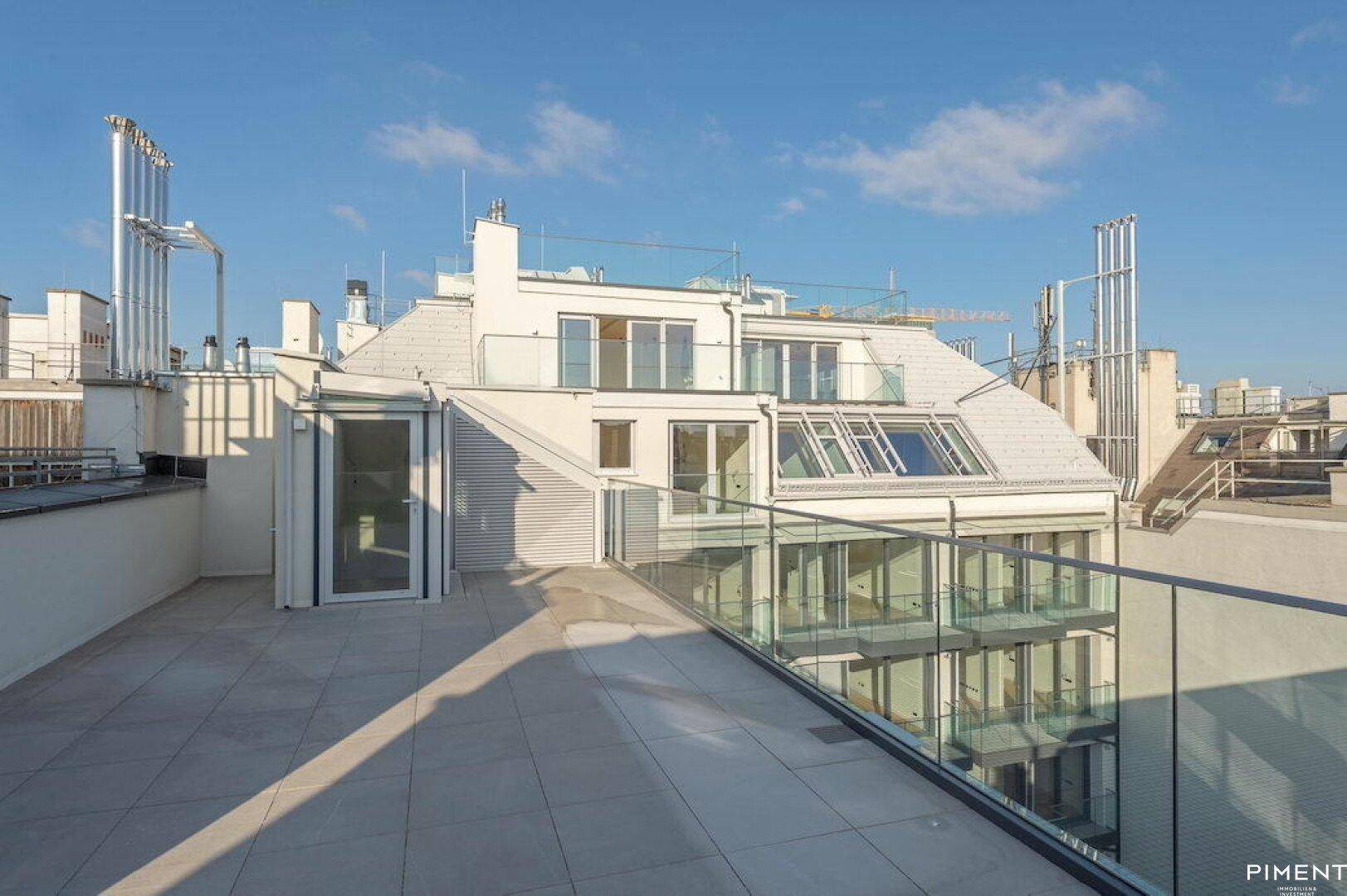 Geräumige Dachterrasse mit Fliesenboden und Glasgeländer, ideal für Entspannung im Freien.