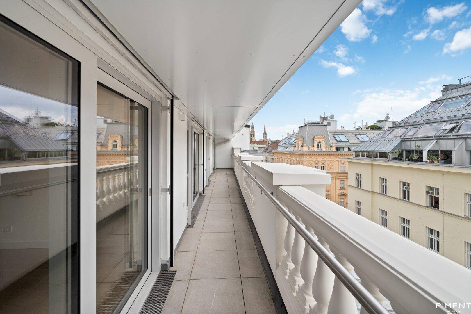 Langer Balkon mit klassischem Geländer und Blick auf die Stadt.