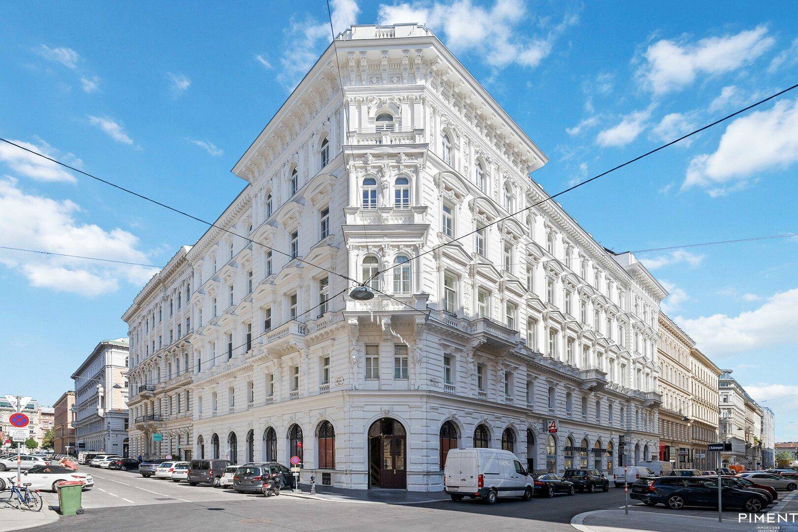 Eindrucksvolles, weißes Eckgebäude mit klassischer Architektur und reich verzierten Fassadendetails.