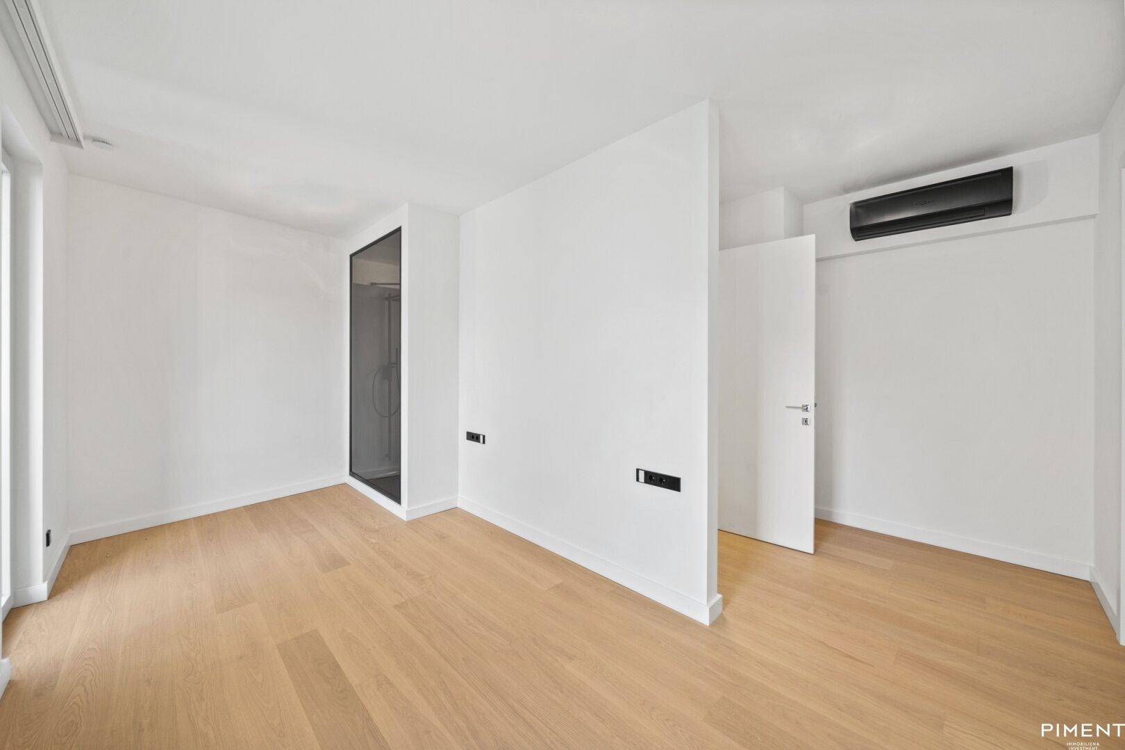 Helles Schlafzimmer mit Parkettboden, Klimaanlage und moderner Raumaufteilung.