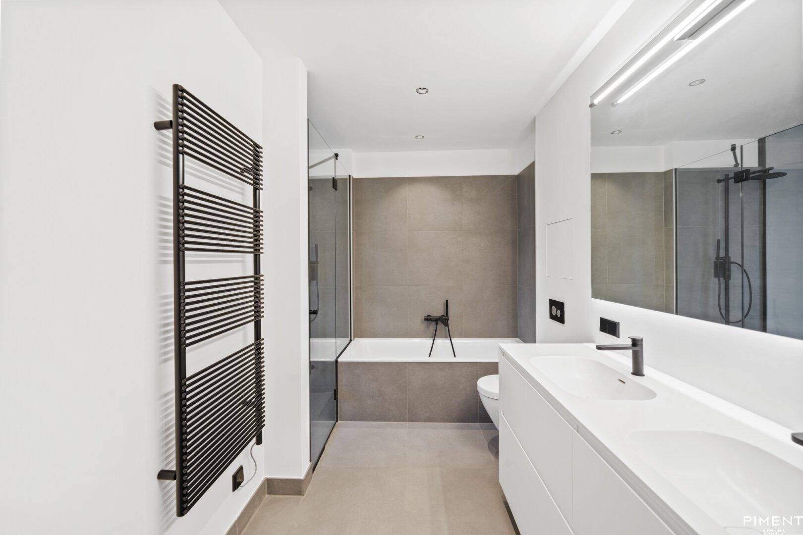 Modernes Badezimmer mit Doppelwaschbecken, Badewanne, Dusche und beheiztem Handtuchhalter.