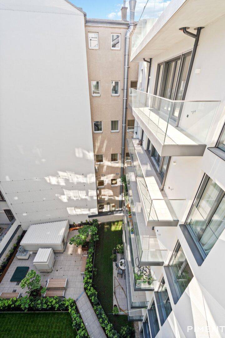 Grüner Innenhof mit Sitzgelegenheiten und Blick auf die umliegenden Balkone der Wohnanlage.