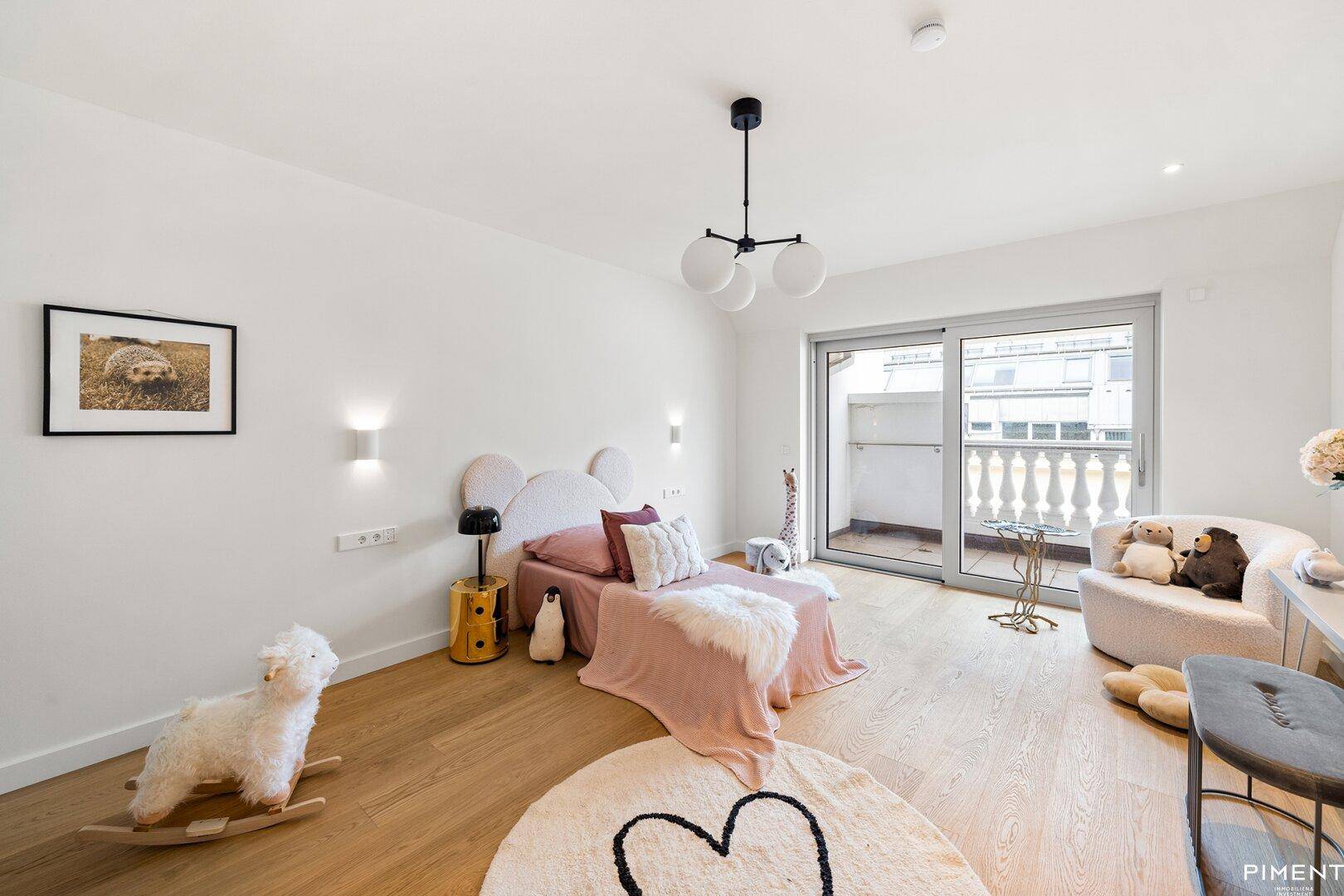 Kinderzimmer mit rosa Bett, Holzboden und Zugang zu einem Balkon.