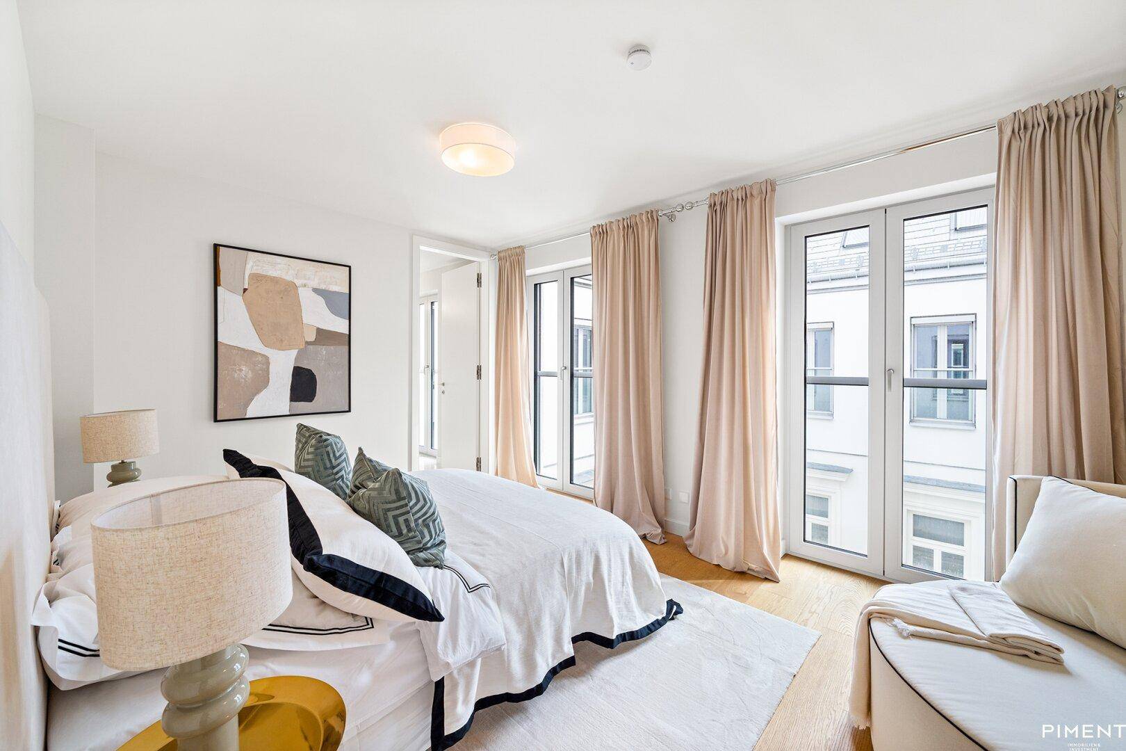 Gemütliches Schlafzimmer mit hellen Vorhängen und Zugang zu einem französischen Balkon.