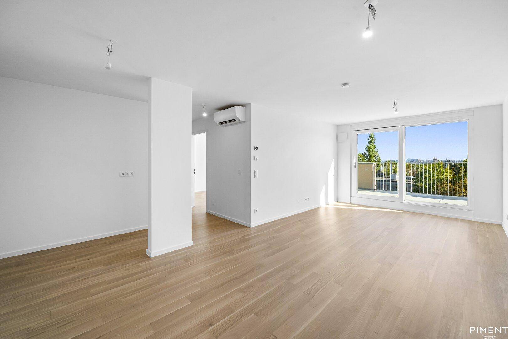 Heller Wohnbereich mit Parkettboden, großen Fenstern und Zugang zum Balkon.