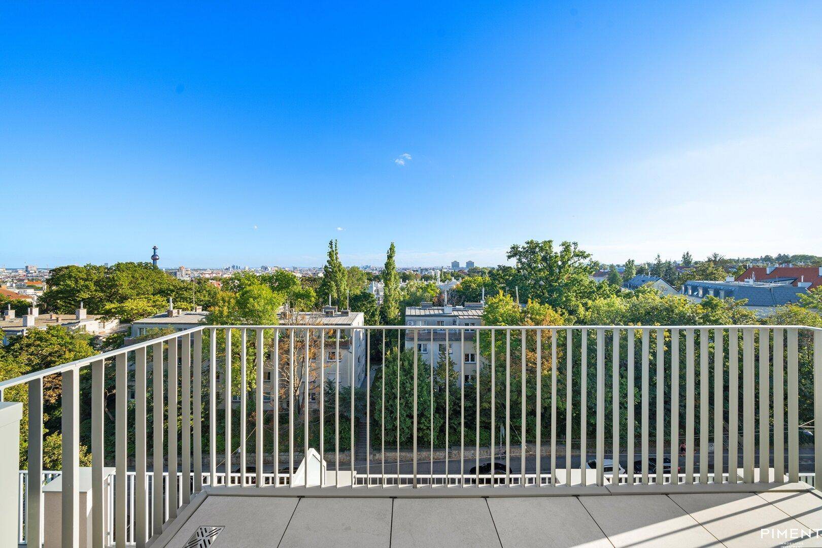 Große Dachterrasse mit weitem Stadtblick und umliegender Natur unter blauem Himmel.