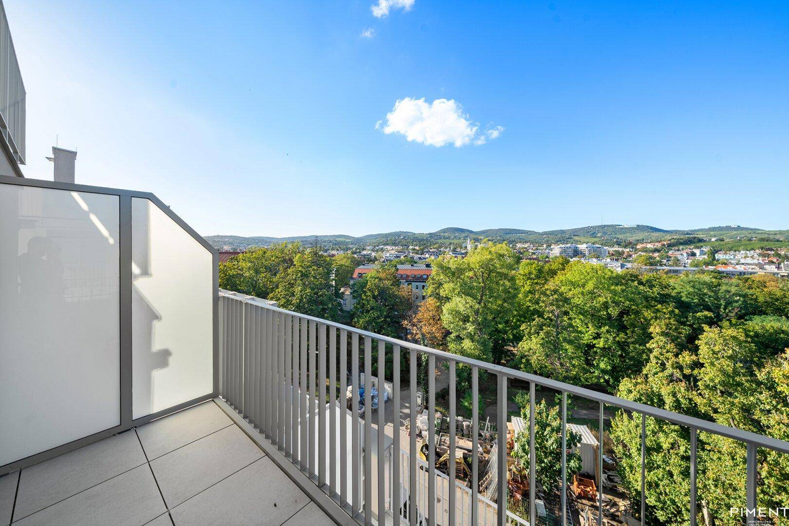 Balkon mit Metallgeländer und weitem Blick über grüne Hügel und die Stadt.