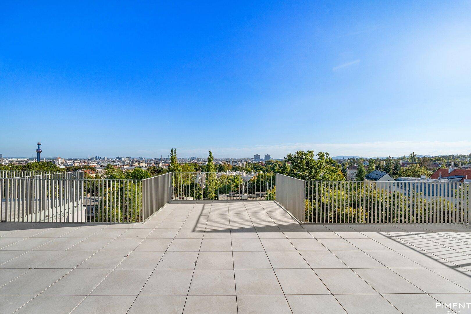 Weitläufige Dachterrasse mit Panoramablick über die Stadt und grüne Umgebung.