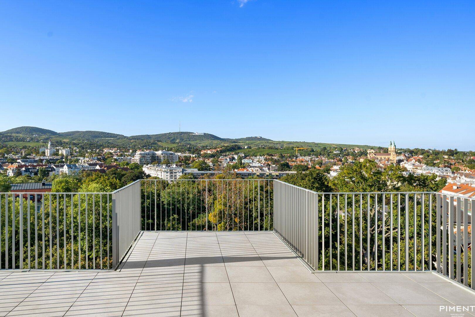 Weitläufige Dachterrasse mit Fliesenboden und beeindruckendem Blick auf die Stadt und die Natur.