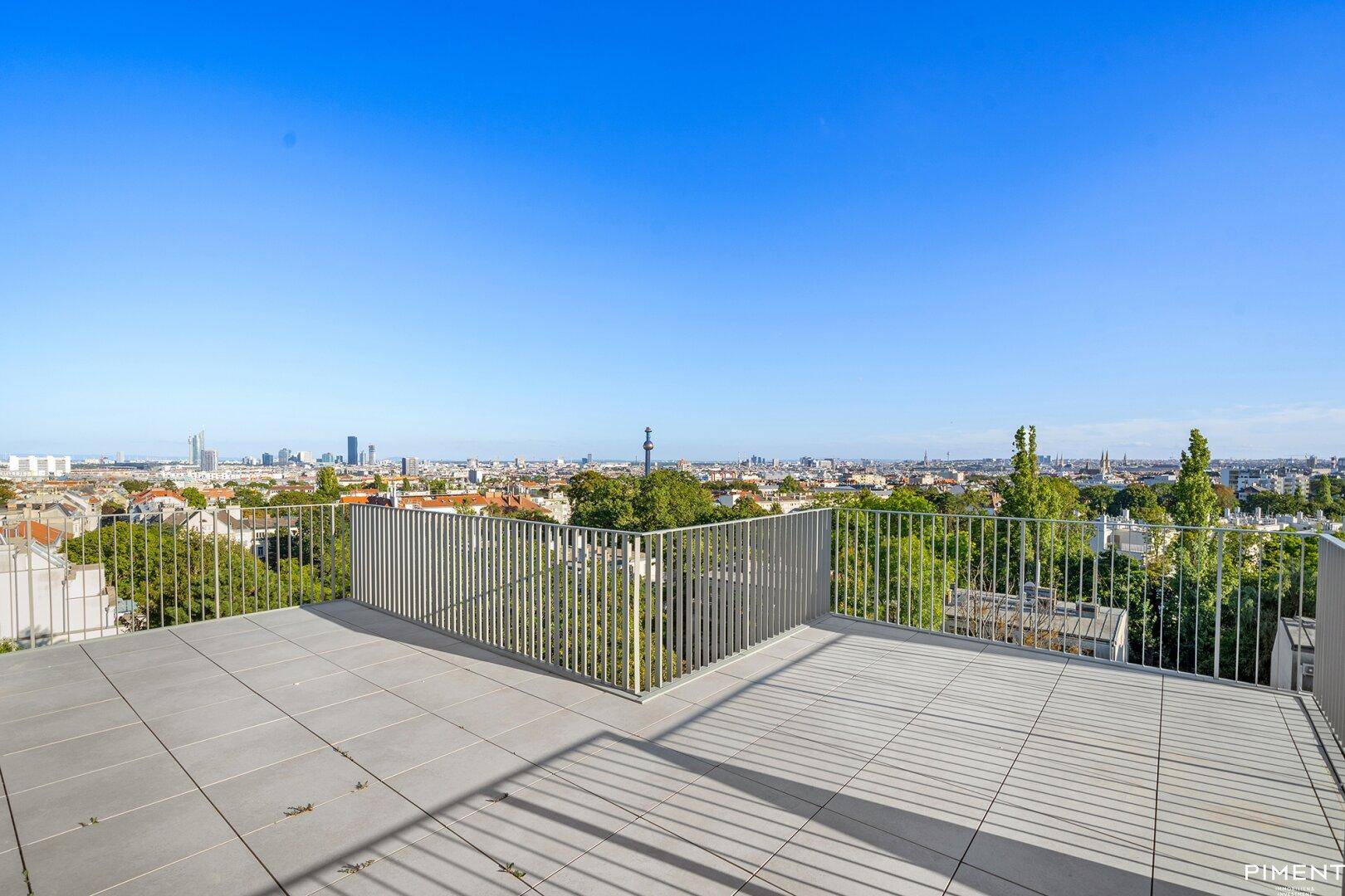 Große Dachterrasse mit weitem Blick über die Stadt und die Skyline am Horizont.