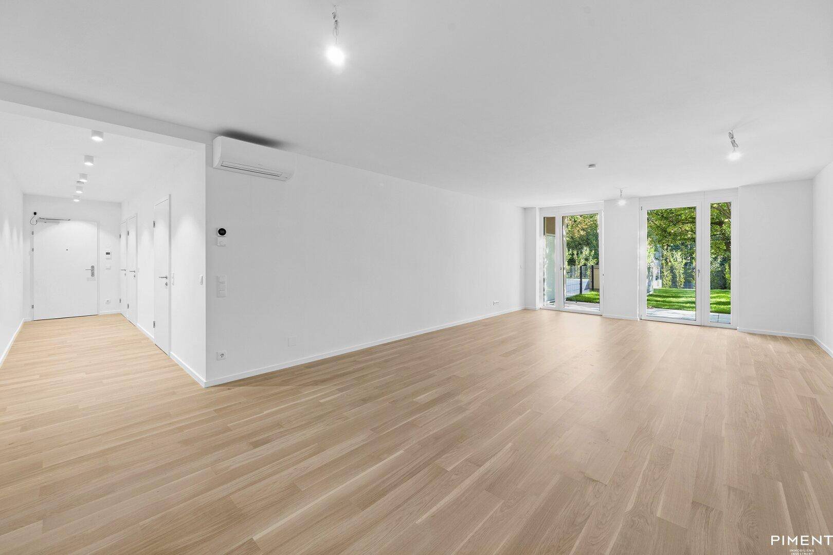 Lichtdurchfluteter Wohnraum mit Parkettboden, Klimaanlage und Zugang zum Eingangsbereich.