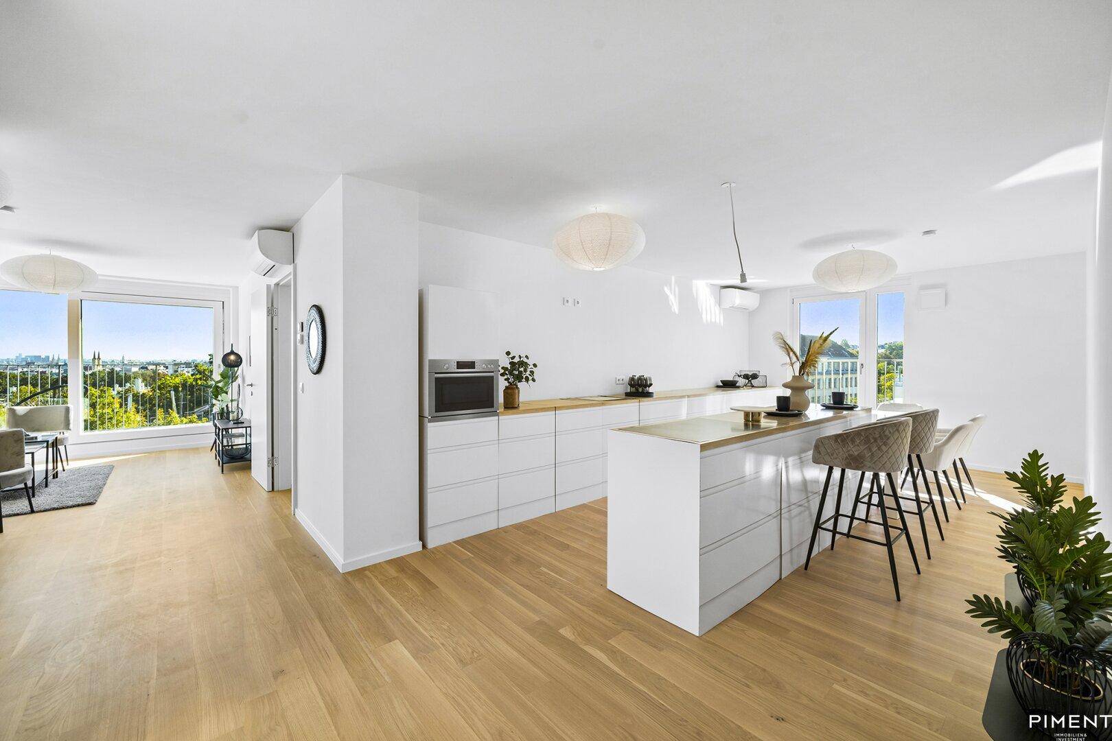 Moderne offene Küche mit weißer Einrichtung, Kücheninsel und Essbereich mit Blick ins Grüne.