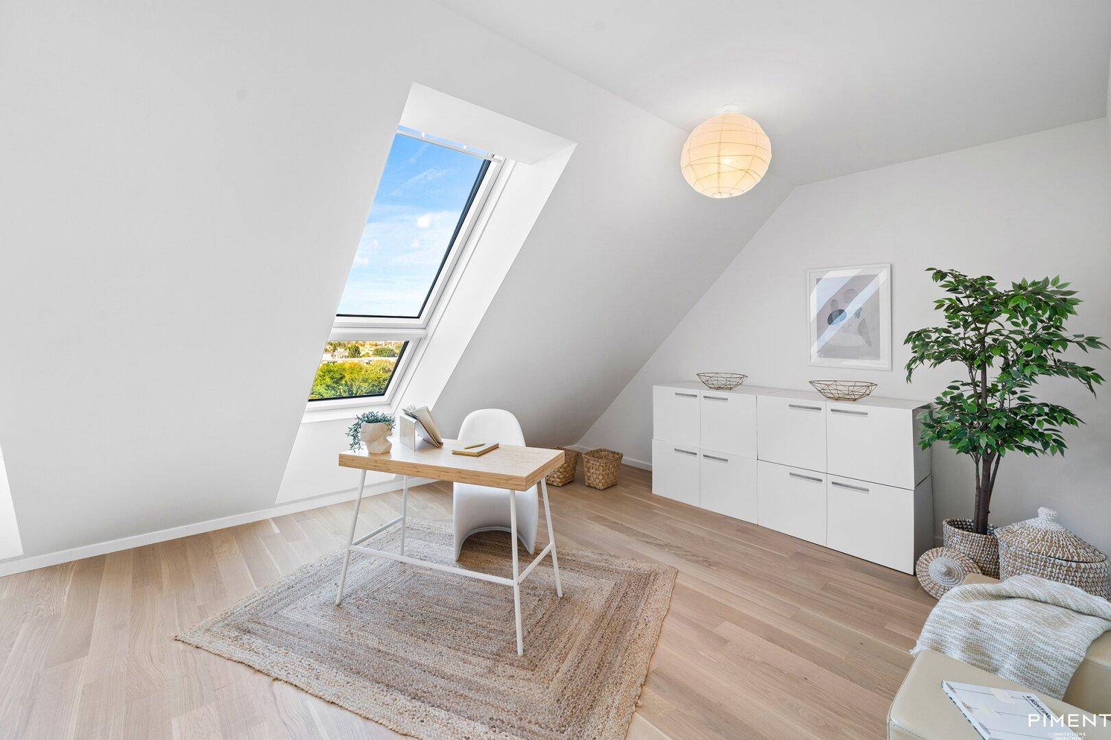 Ruhiges Arbeitszimmer im Dachgeschoss mit Schreibtisch und Blick ins Grüne durch das Dachfenster.